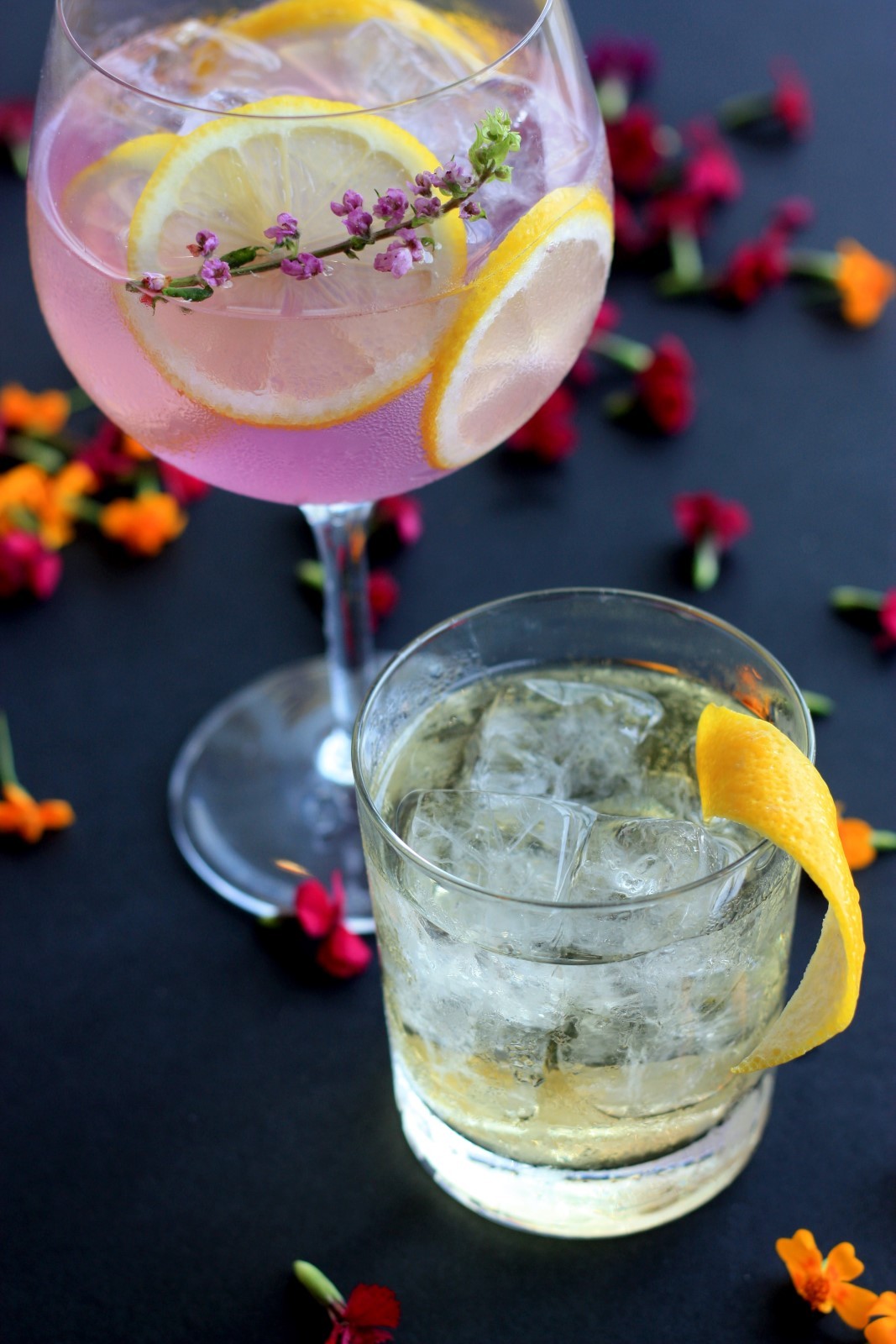 Δύο ποτήρια με υγρό και παγάκια γεμάτα από φέτες λεμονιού και βρώσιμα λουλούδια