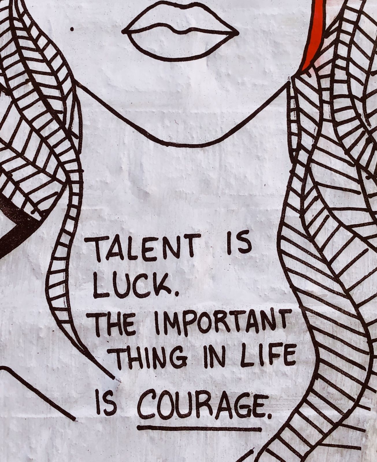 Απεικόνιση σε τοίχο γυναικείου προσώπου με moto που λέει ότι το ταλέντο είναι τύχη και το σημαντικότερο είναι το κουράγιο