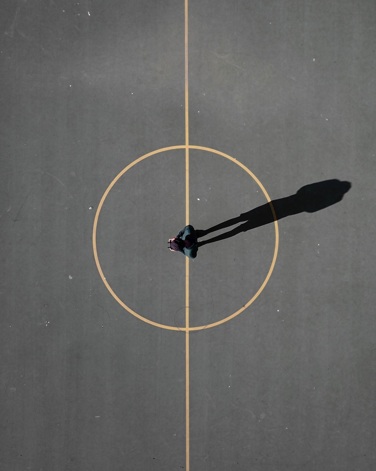Σκιά μιας αντρικής φιγούρας στην μέση ενός γηπέδου μπάσκετ