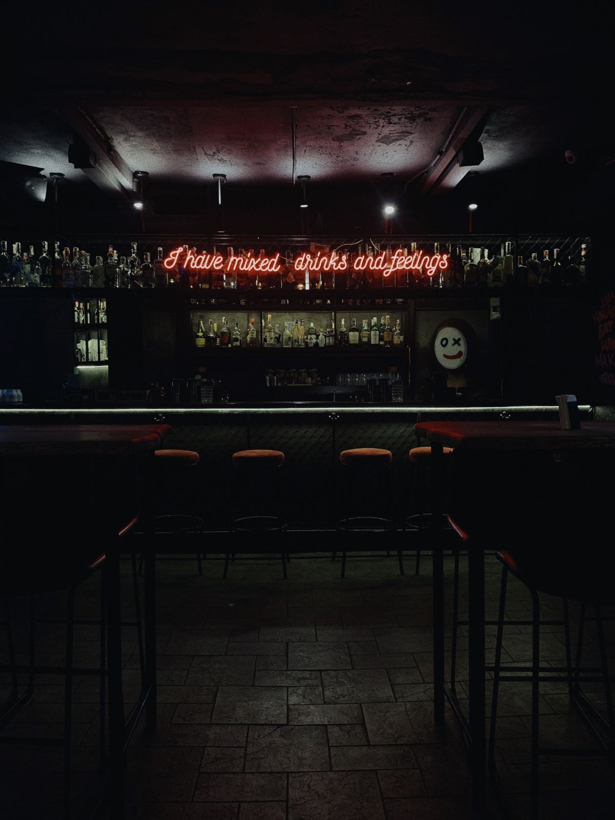 Ένα bar εσωτερικά σε ημίφως με φωτισμένη επιγραφή νέον στον τοίχο του