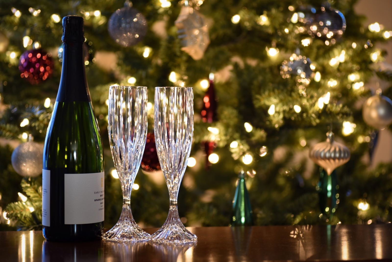 Σαμπάνια και ποτήρια μπροστά σε χριστουγεννιάτικο δέντρο